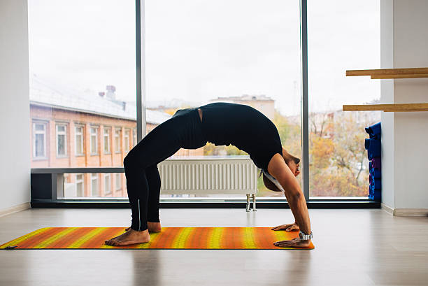 pratique du yoga. homme faisant bridge pose à l’intérieur de la pièce avec panoramique - yoga men bridge bending over backwards photos et images de collection