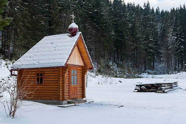 A small church in the snow is in the forest of the Carpathians around the centuries-old pine trees covered with snow. Mountain Dragobrat, western Ukraine.