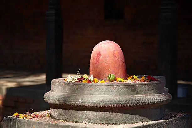 Shivalingam - symbol of fertility in Hinduism. Shiva linga covered with colorful flowers on the streets of Kathmandu, Nepal. Worship of a penis in Hinduism