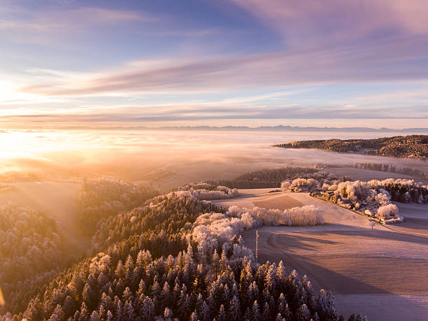 上からの日の出 - 雪のオーストリアの風景の上に黄金の霧 - ウィンターワンダーランド ストックフォトと画像