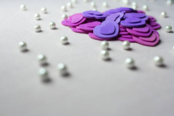 istock Purple hearts and pearls lying on a beige fabric 637712436