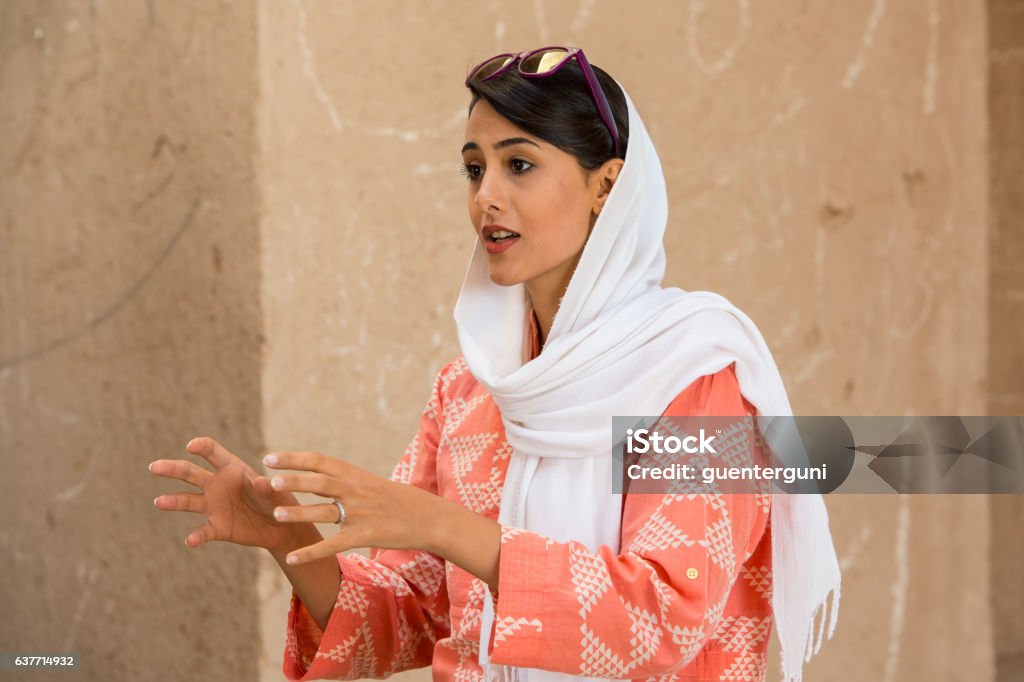 Female iranian tourguide wearing a headscarf, Yazd, Iran Young female ianian tourguide with a typcial simple headscarf (hijab or rousari) while she is working as tourist guide at the towers of silence in Yazd, Iran. Elegance Stock Photo