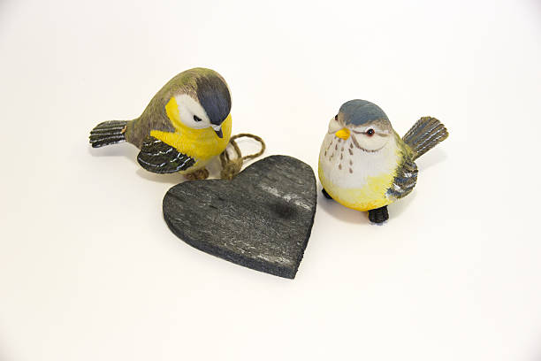 Two toy birds next to a wooden heart Two toy birds next to a wooden heart dearness stock pictures, royalty-free photos & images