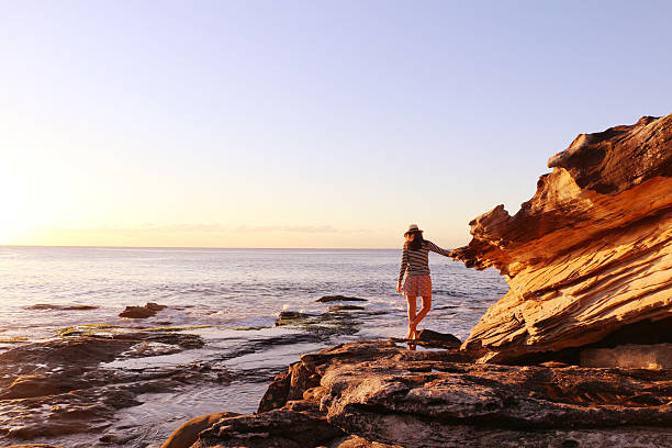 Girl enjoying the sunrise in front of the ocean Girl enjoying the sunrise on the rocks in front of the ocean in Sydney Australia. bondi beach sunrise stock pictures, royalty-free photos & images