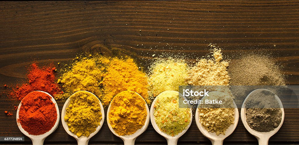 Powder spices and wooden spoons on wooden table Spilled powder spices and wooden spoons on the table - Top view Spice Stock Photo