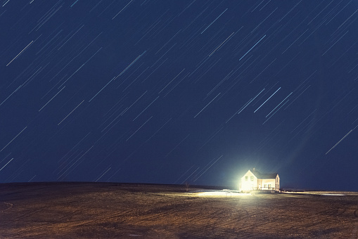 The stars rain down on a distant farmhouse.  Long exposure.