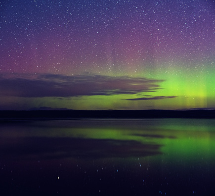 The Northern lights shimmer over an absolutely still lake.  Long exposure.