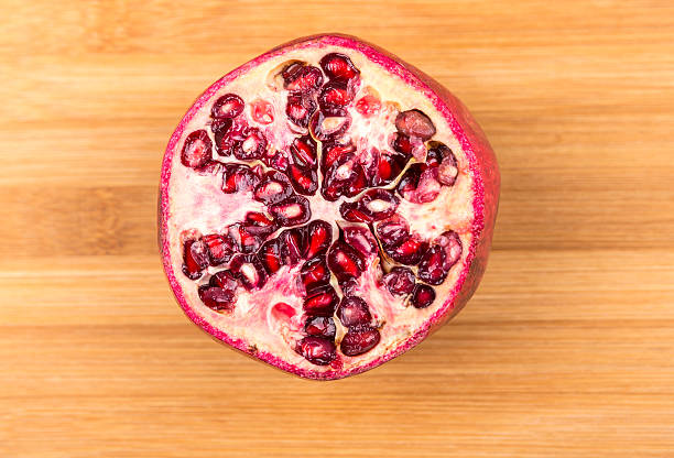 Whole and cut ripe pomegranate isolated on a wood background