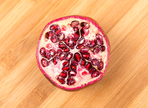 Whole and cut ripe pomegranate isolated on a wood background