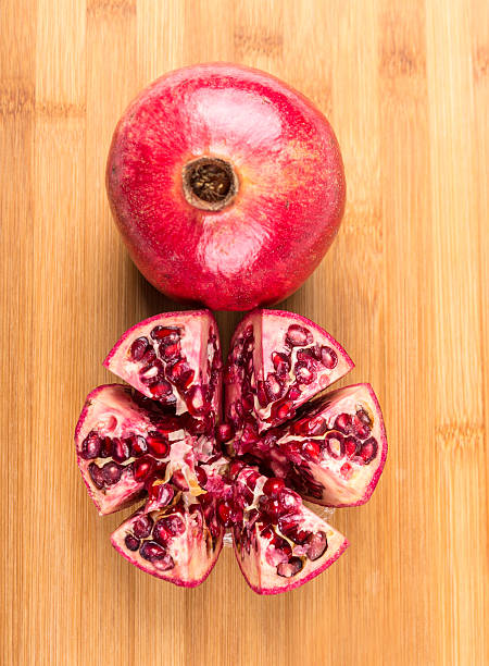 Whole and cut ripe pomegranate isolated on a wood background