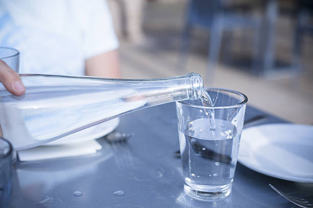 pouring distilled water into a clear glass at a restaurant - water water bottle glass pouring imagens e fotografias de stock