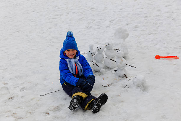 istock little boy building snowman in winter nature 637743494