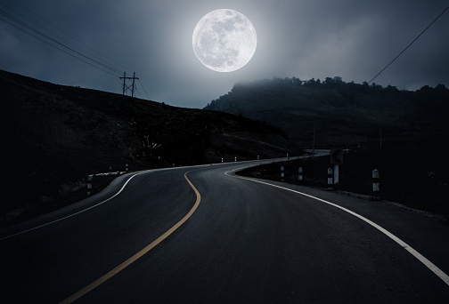 Landscape of full moon with curvy roadway in forest at national park. Mountain winding road passing, outdoors at night. Dark tone. The moon taken with my own camera, no NASA images used.