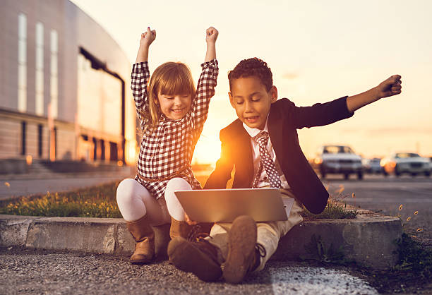 Happy business kid using laptop and celebrating their success at sunset.
