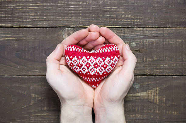 istock men's hands holding red knitted heart 637750392