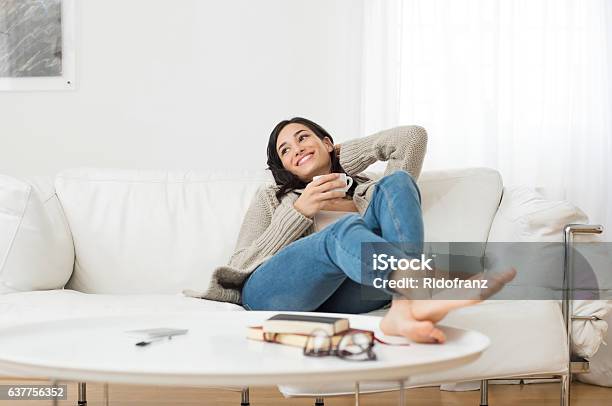 Smiling Woman Thinking On Sofa Stock Photo - Download Image Now - Women, Sofa, Relaxation