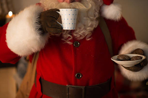 Santa Claus eating cookies and drinking milk stock photo