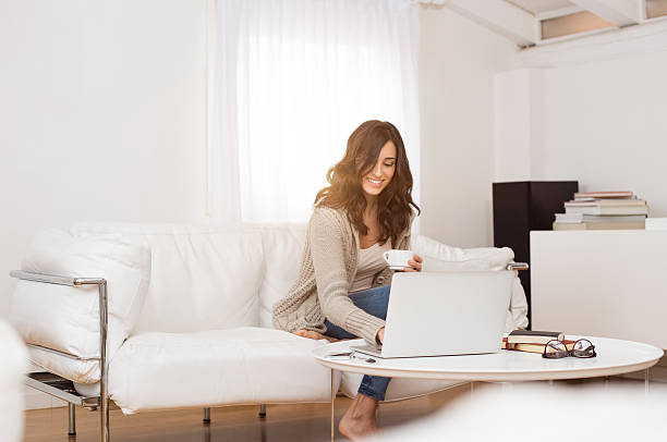 mujer usando una computadora portátil en su hogar  - women computer home interior brown hair fotografías e imágenes de stock