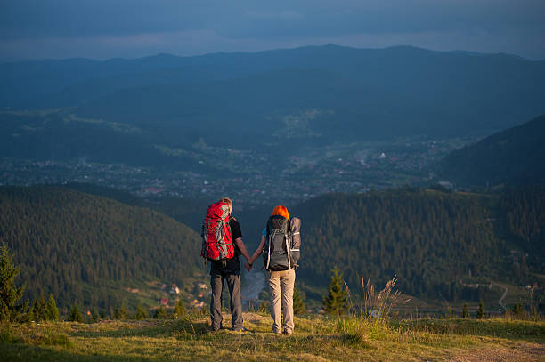 istock Pair holding hands standing on the ridge of hill 637758408