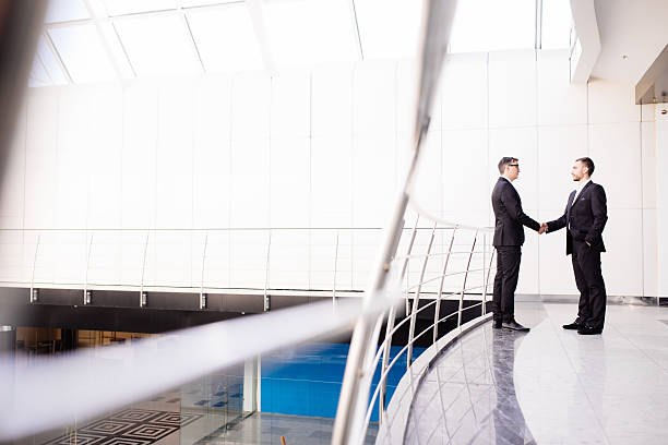 istock side view of businessmen shaking hands in office building 637759630