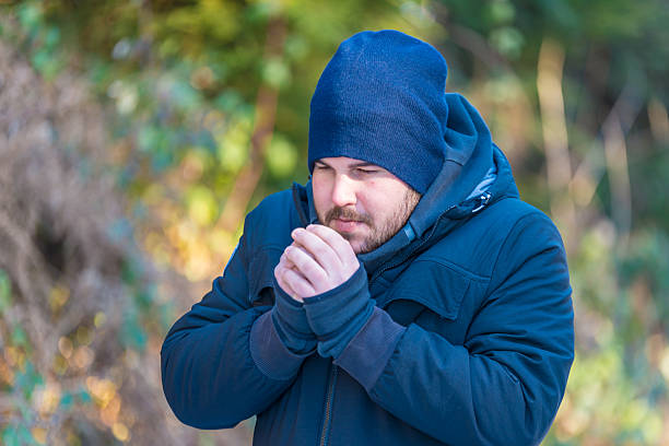 hombre en el calentamiento de sus manos con su aliento - clima polar fotografías e imágenes de stock