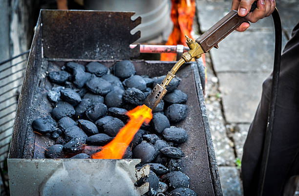 Firing up charcoal briquettes for the BBQ grill. Firing up charcoal briquettes for the BBQ grill. Starting a grill with propane gas torch. grill lighter stock pictures, royalty-free photos & images