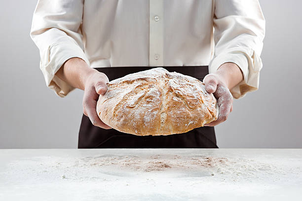 istock Baker man holding rustic organic loaf of bread in hands 637767074