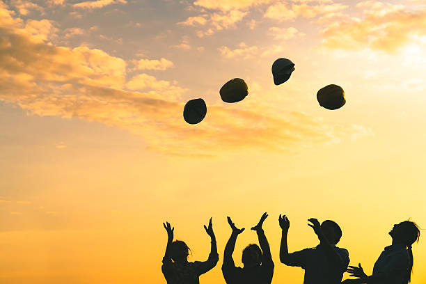 Silhoutte of construction engineers throwing safety helmets on sunset sky