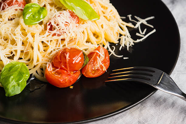 Pasta with tomatoes and basil on the dark background