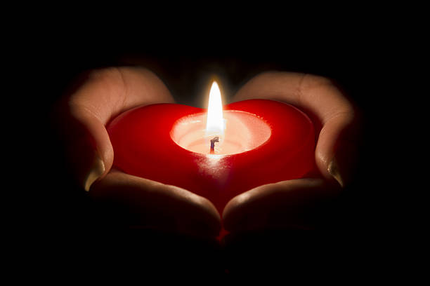istock woman's hands holding a heart shaped candle in the dark 637770158