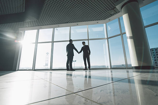 istock side view of businessmen shaking hands in against panoramic windows 637770630