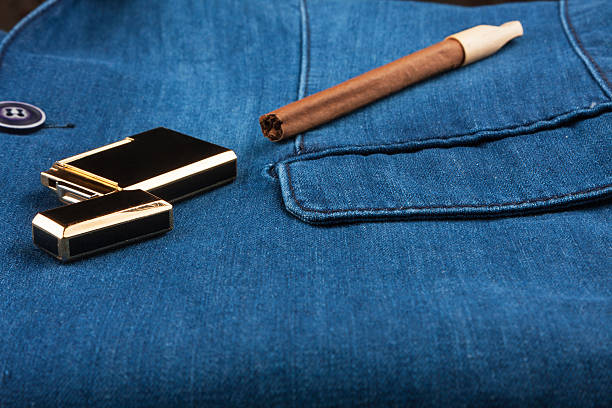 istock Cigar and gold lighter lying on a blue denim jacket 637772030