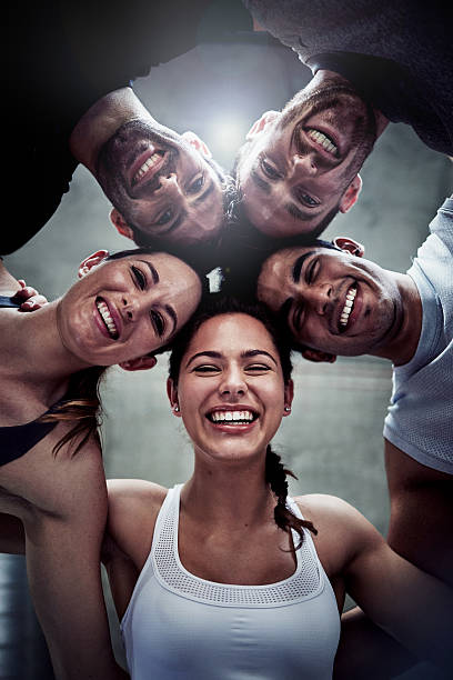 Our circle of strength Portrait of a group of fit young friends huddled together in solidarity at the gym community health center stock pictures, royalty-free photos & images