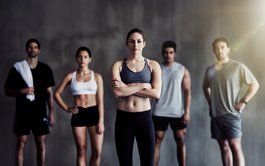 Portrait of a determined young woman standing in front of a fitness group
