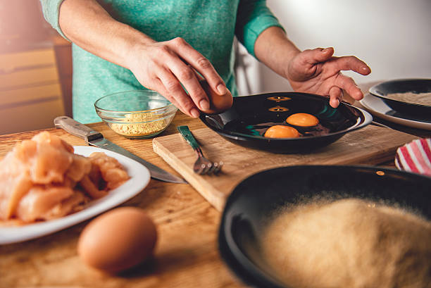 donna che cucina e rompe le uova nel piatto - break eggs domestic kitchen breaking foto e immagini stock