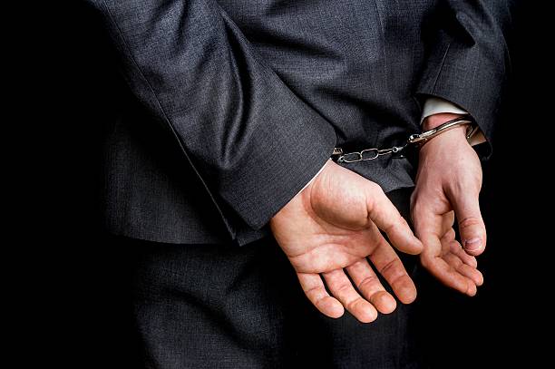 istock Arrested businessman in handcuffs with hands behind back 637773894