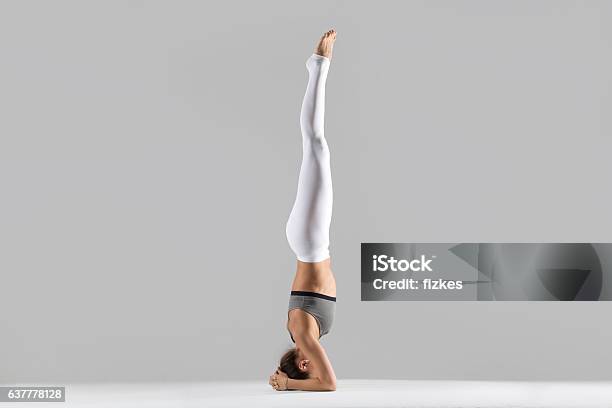 Young Woman In Salamba Sirsasana Pose Grey Studio Background Stock Photo - Download Image Now