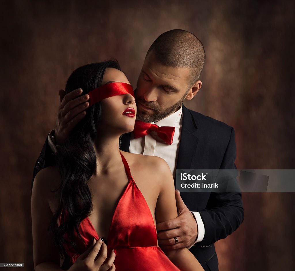 Sexy Couple Love Kiss, Fashion Man Kissing Sensual Woman, Blindfold Sexy Couple Love Kiss, Man in Suit Kissing Sensual Woman, Red Fashion Blindfold on Girl Eyes Sensuality Stock Photo