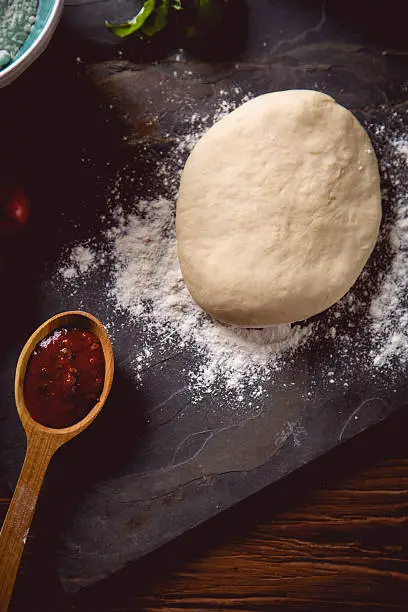 Photo of Dough with flour on wooden table, preparing homemade pizza