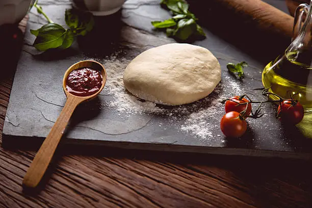 Photo of Dough with flour on wooden table, preparing homemade pizza