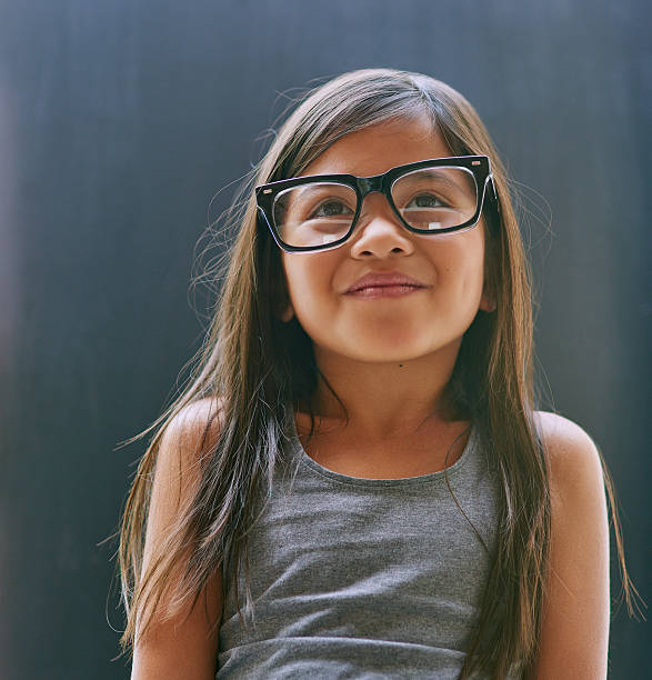 Studio shot of a little girl wearing spectacles against a dark background