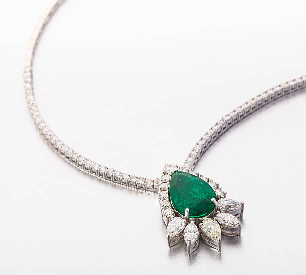 Vintage emerald pendant with diamonds hanging on gold chain on black background