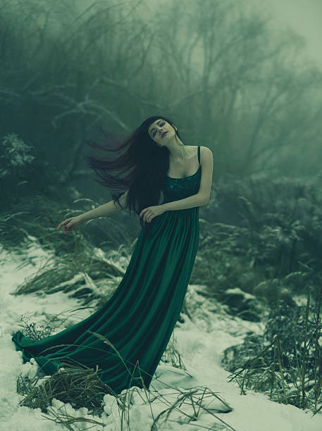 Art photography with an atmosphere of calm and melancholy. The girl with long hair is walking in the winter garden. She is dressed in a long green dress. The sensation shot underwater. Creative colors.