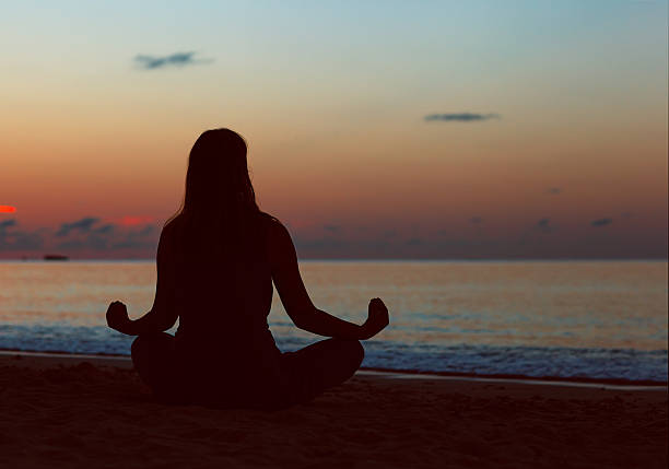 istock young woman meditation on sunset beach 637789852
