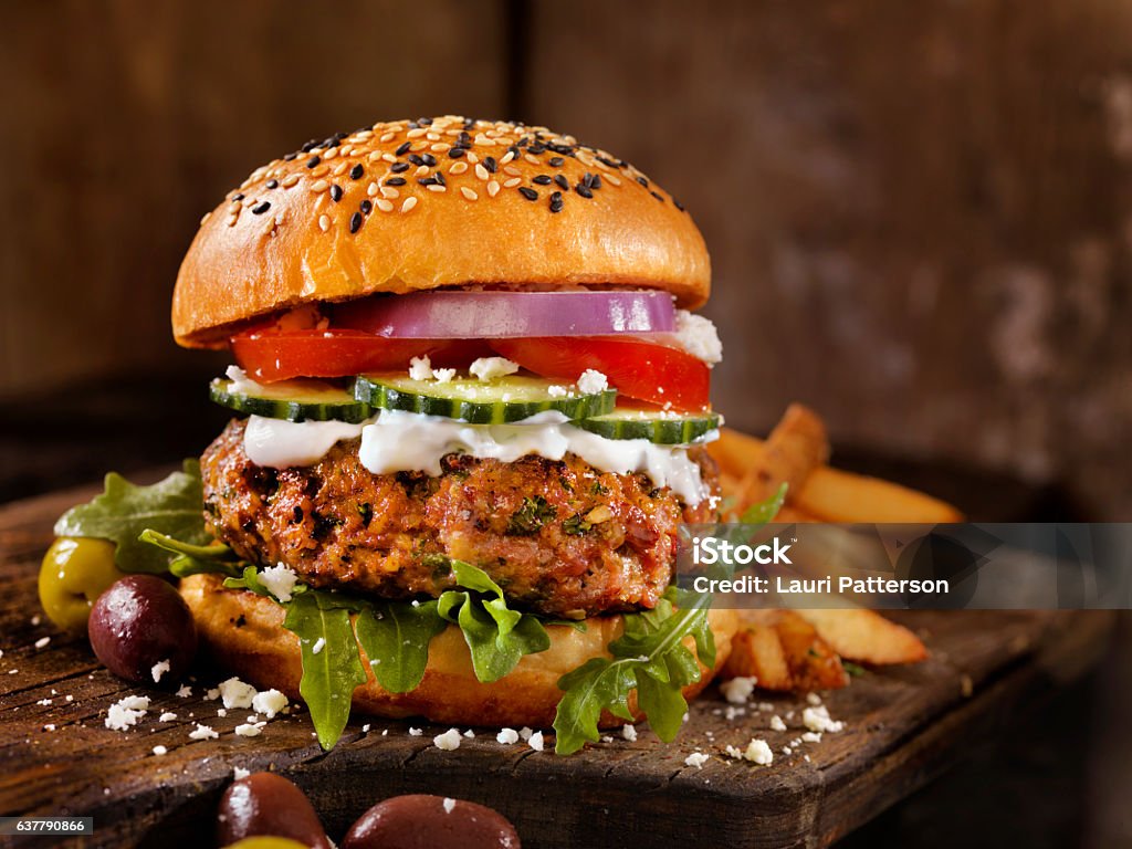 100% Lamb -Greek Burger 100% Lamb -Greek Burger with Arugula, Cucumber, Tomatoes, Feta and Tzatziki Sauce - Photographed on Hasselblad H3D2-39mb Camera Burger Stock Photo