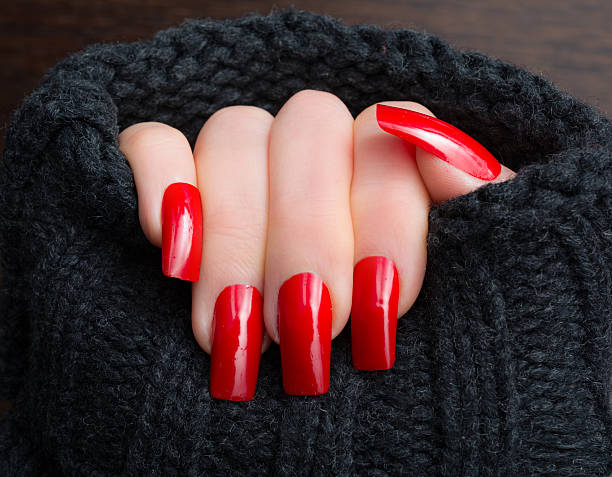 kobieta pokazująca swoje nowe paznokcie i ponadwymiarowy wełniany sweter - red nail polish zdjęcia i obrazy z banku zdjęć