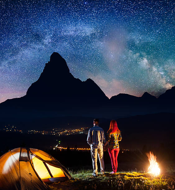 istock Tourists holding hands, standing near camp and enjoying starry sky 637792128