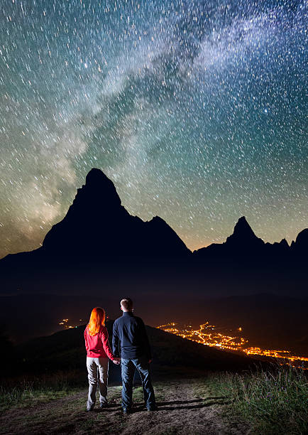 istock Pair holding hands, standing on hill and enjoying starry sky 637792412