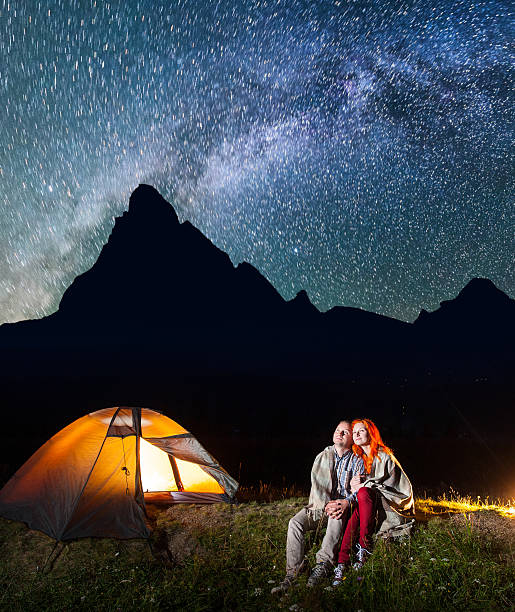 istock Two lovers covered with a plaid sitting together near campfire 637793544