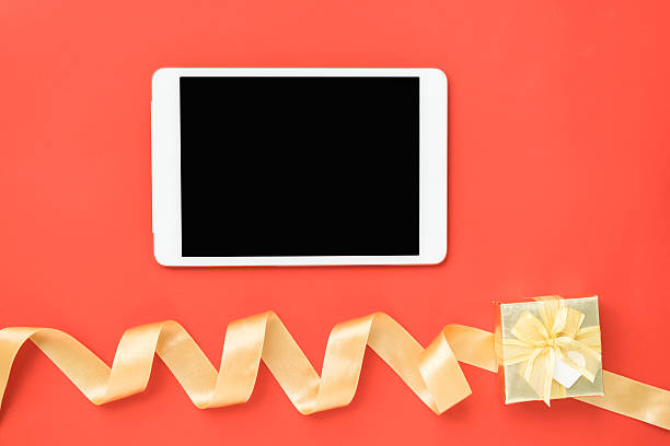 istock Top view of tablet and gold ribbon gift box 637793810